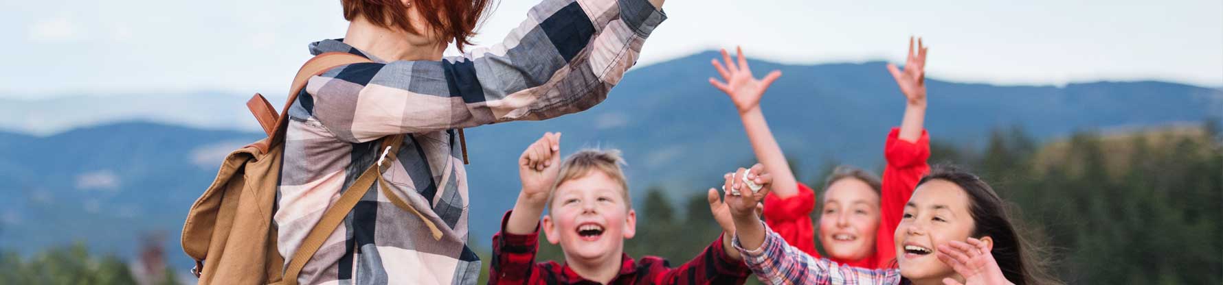 Kinder spielen mit ihrer Erzieherin im Freien mit einem Ball